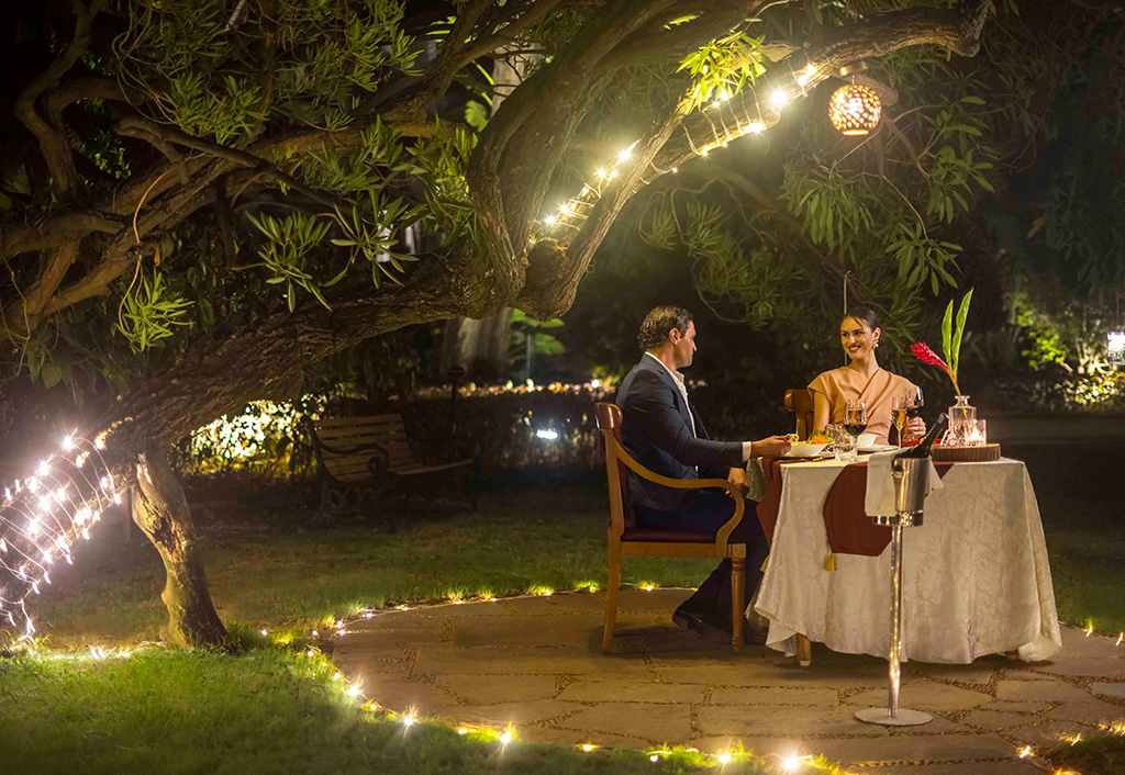 Couple dining outdoors at The Oberoi Bengaluru, under tree lights.