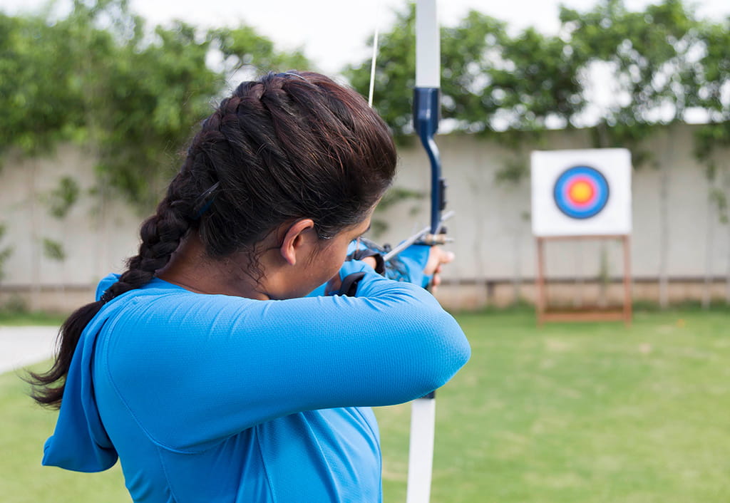 Archer aiming bow at target, grassy area at The Oberoi Sukhvilas