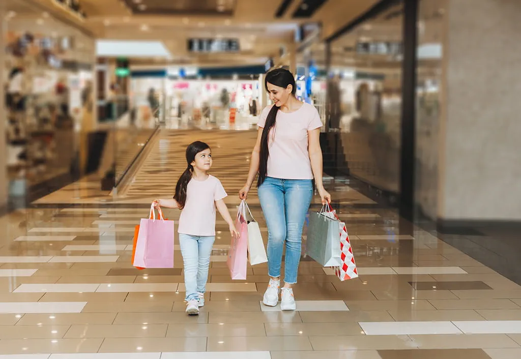 Woman and child shopping in a mall carrying bags, family outing
