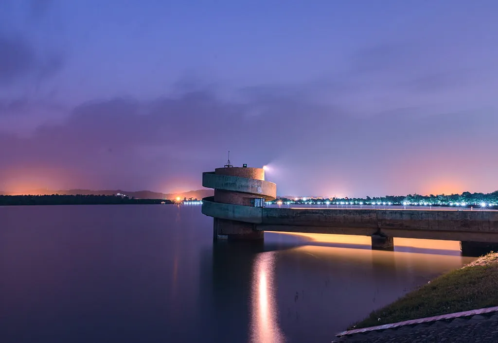 Illuminated tower over nighttime lake, hills, near 5-star Oberoi Sukhvilas resort