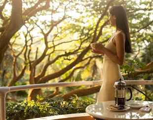 Woman enjoys coffee on The Oberoi Bengaluru balcony.