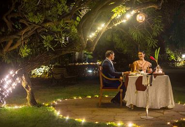 Couple dining outdoors at The Oberoi Bengaluru, under tree lights.