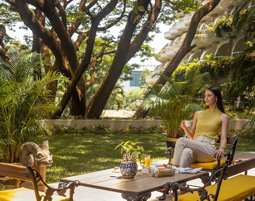 Woman enjoying coffee in garden at The Oberoi Bengaluru.