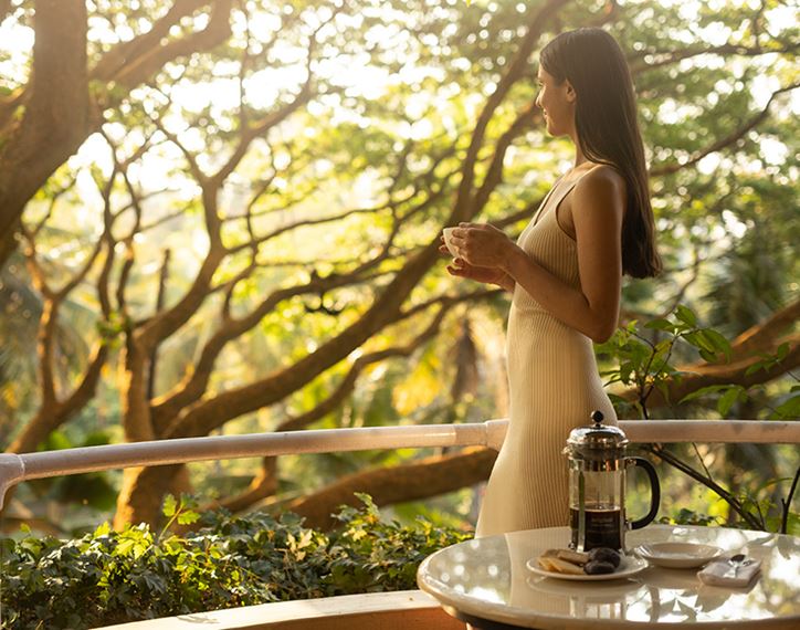Two people relaxing by pool, The Oberoi Bengaluru, trees.