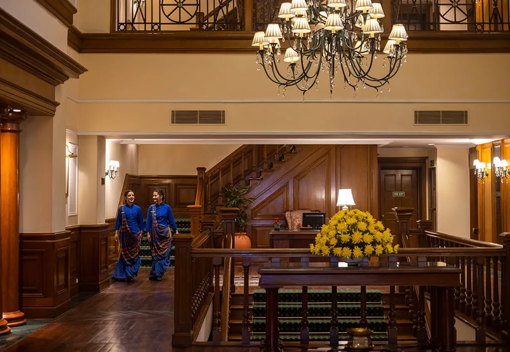 "Hotel lounge with two staff walking; elegant wooden decor; The Oberoi Cecil"