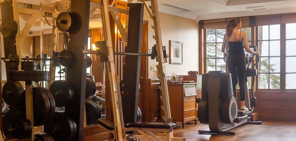 Woman exercises on elliptical in luxury gym at The Oberoi Cecil