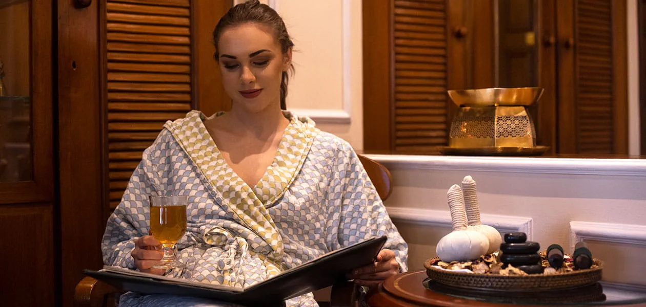 Woman reading with drink at luxury hotel, The Oberoi Cecil