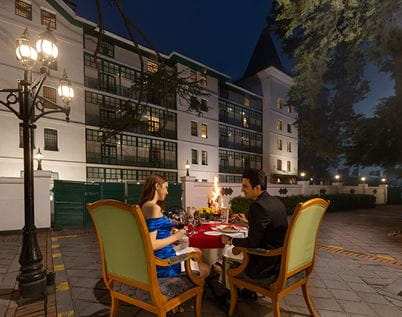 Couple dining outdoors at night at luxury hotel, The Oberoi Cecil