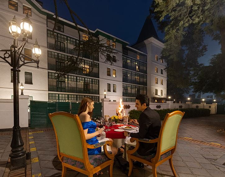 Couple dining outdoors at night at luxury hotel, The Oberoi Cecil