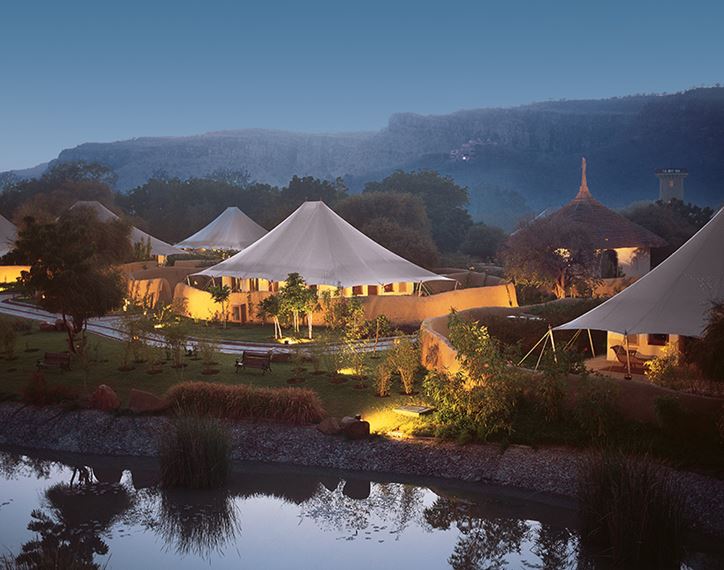 Luxury tents illuminated at night by a serene lakeside setting