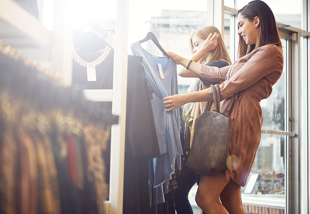Two women shopping for clothes in a brightly lit store