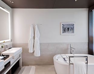 Elegant bathroom with bathtub and robes in The Oberoi New Delhi
