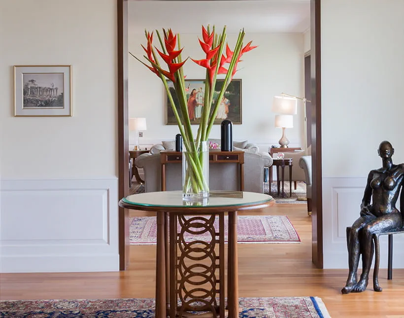 A glass vase with red flowers on table in luxurious room at The Oberoi New Delhi, a 5-star hotel