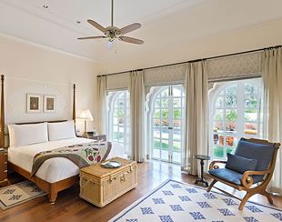 Luxury bedroom with elegant decor, garden view at The Oberoi Sukhvilas.