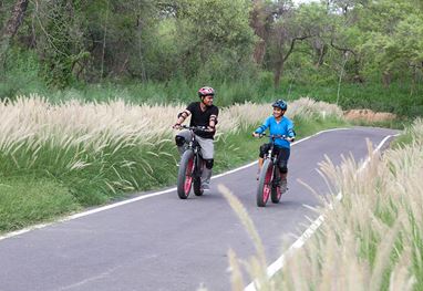 Two people cycling on a forest path near The Oberoi Sukhvilas