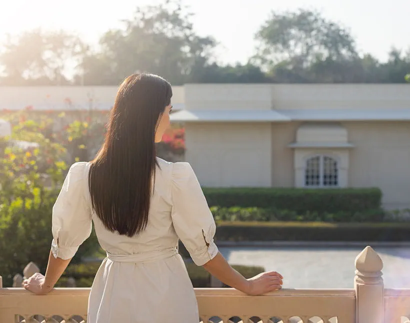 A woman in white dress overlooks gardens at The Oberoi Sukhvilas