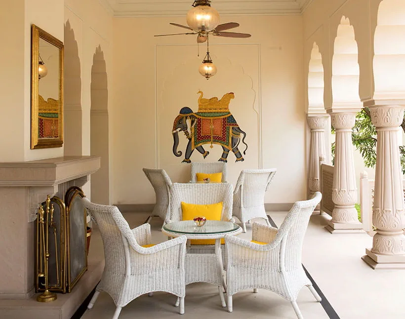 White wicker chairs on patio near elephant mural at luxury resort