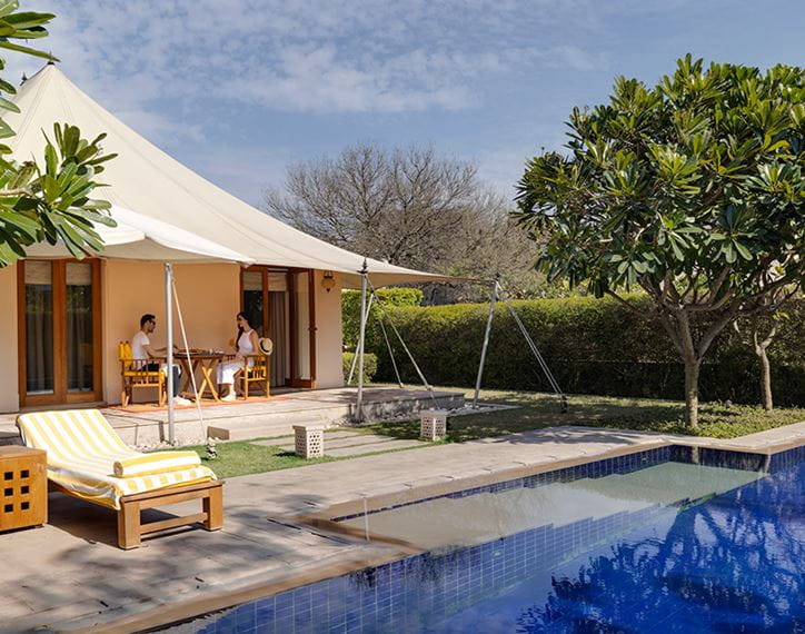 Couple dining outside luxury tent, poolside at The Oberoi Sukhvilas