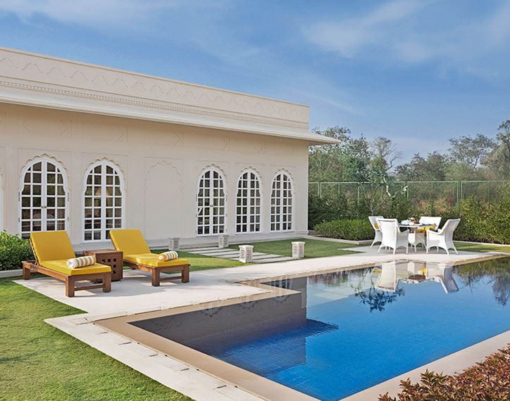Resort poolside with loungers and table, The Oberoi Sukhvilas.