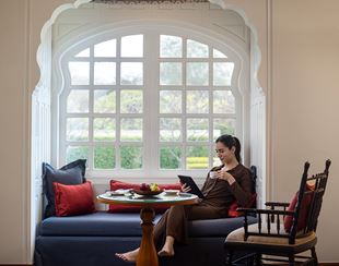 Woman reading tablet, drinking coffee in luxury suite, The Oberoi Sukhvilas