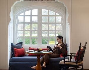 Woman reading tablet, drinking coffee in luxury suite, The Oberoi Sukhvilas