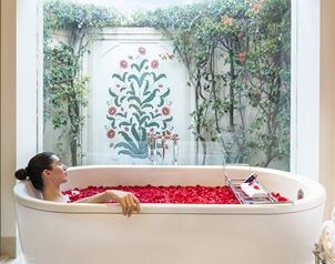 A woman relaxes in rose petal bath, The Oberoi Sukhvilas.