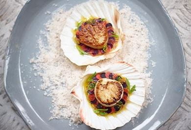 Scallops cooked in shell with brown butter and spring vegetables