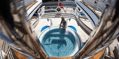 A woman sits beside a luxury spa pool on the lower deck of the Escape Majesty 155 superyacht